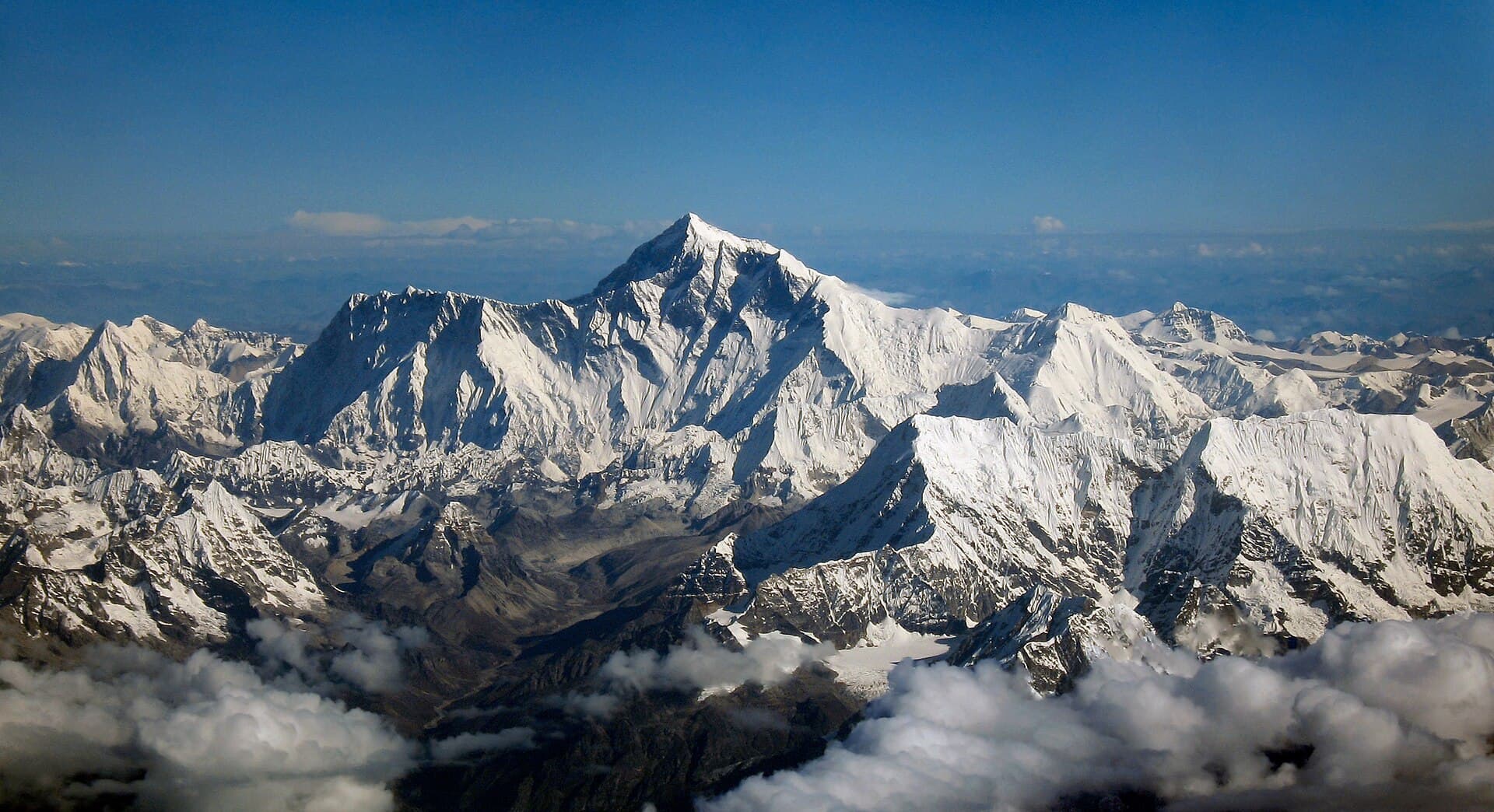 View northward to Mount Everest from an aircraft from airline company Drukair in Bhutan . The aircraft is south of the mountains, directed north. Mount Everest is above the ridge connecting Nuptse and Lhotse.